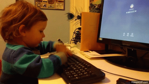 a little boy plays with an computer keyboard
