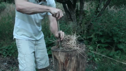 a man with an odd helmet using a brush to cut grass