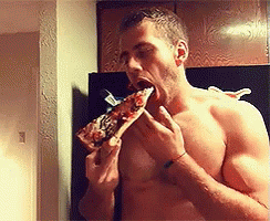 shirtless man eating a pizza in the mirror