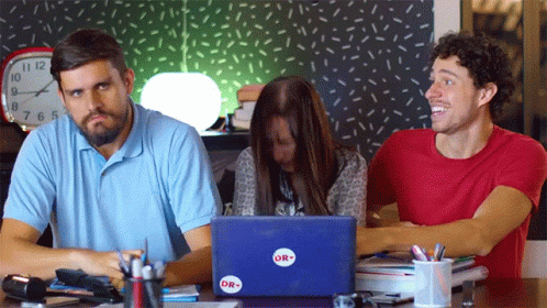 three people looking at a laptop on a desk