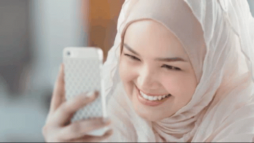 a woman in white is smiling while holding her cell phone