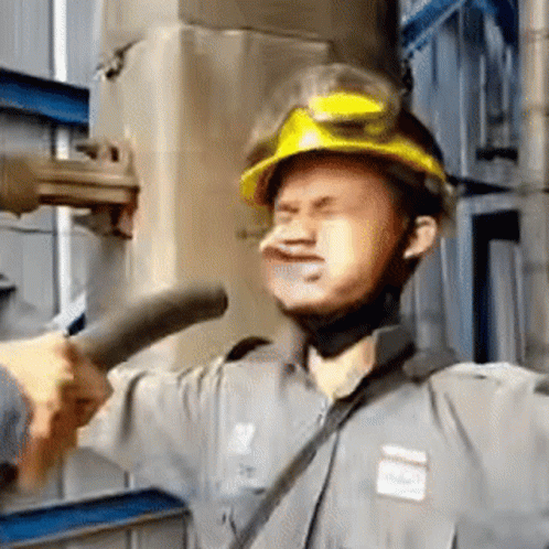 a man wearing a work hat and holding up some pipe