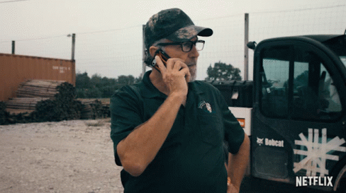 a man is talking on the phone in front of a truck