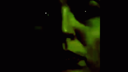 a woman's face is glowing green as it appears to be illuminated in the dark
