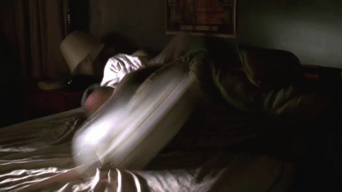 a person laying in bed under a blanket with their arms open