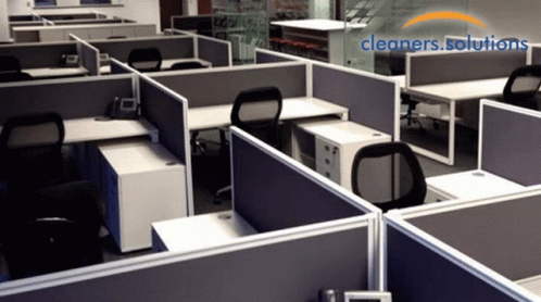 a number of cubicles with computer screens and telephones