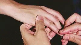 two people are touching each other while they are getting their wedding rings
