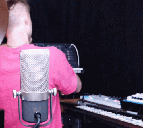a person standing next to some keyboards in a music studio