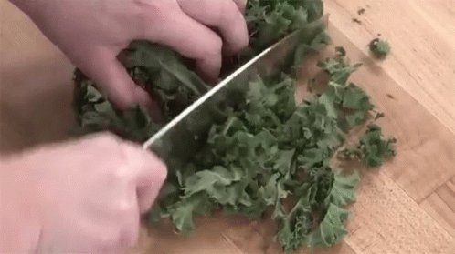 someone chops green leafy vegetables with scissors