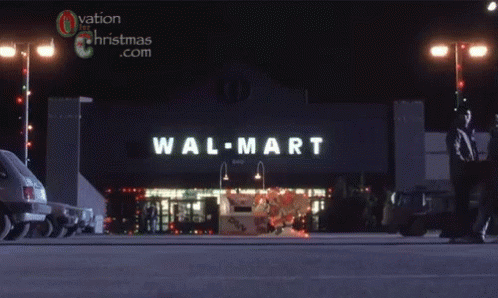 two people walk into a wal - mart shopping center at night