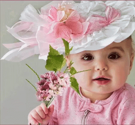a baby holding flowers wearing a hat