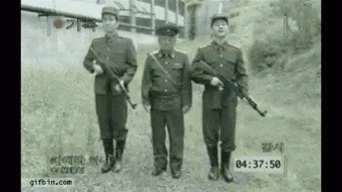 two men wearing uniforms and holding guns in front of a train