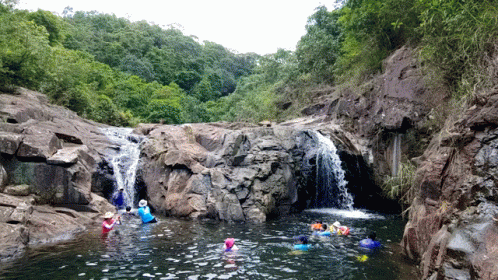 several people float in the water near some rocks