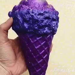 a person's hand holding an ice cream cone