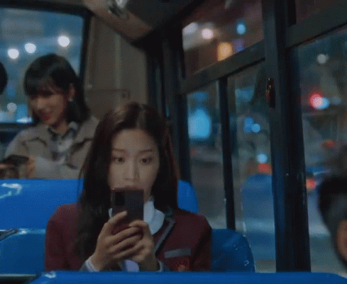 three people sitting down in a bus using phones