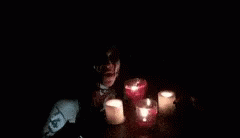 two people sit in the dark with candles lit around them