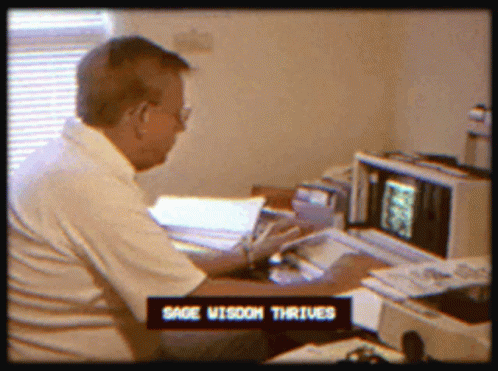 a man in glasses works on a computer in an office