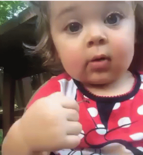an infant girl who has been making faces with her hand