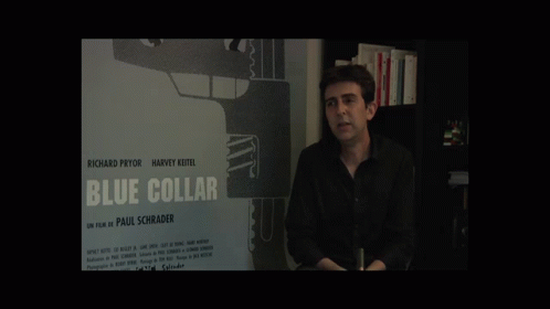 man in front of posters for blue collar