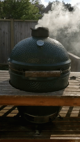 a smoke billowing out from the top of an over sized barbecue grill