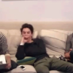 three people sitting on a couch with a wii remote