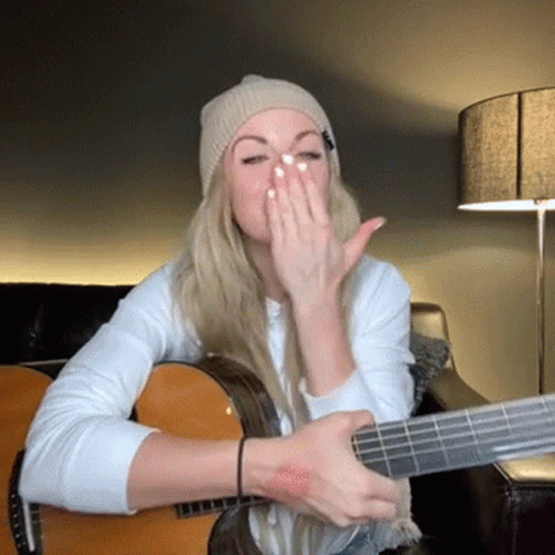 a woman that has her face covered while playing guitar