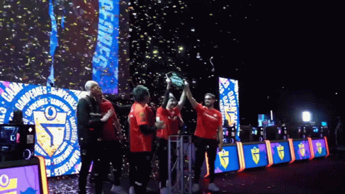 two teams holding a soccer trophy as confetti falls over them