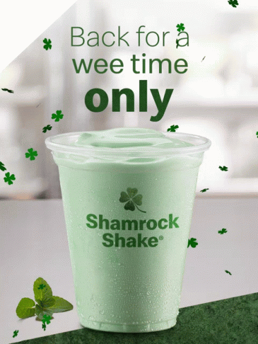 a green starbucks drink with shamrock leaves in the background