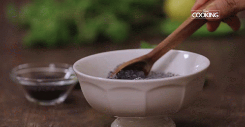 a spoon in a bowl with a spoon in it and a bowl with a chocolate mixture and another cup with black sugar