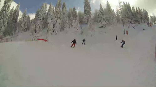 four snowboarders and one skier are making their way down a hill