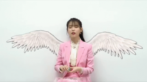 a woman wearing a purple jacket and white shirt with angel wings on it