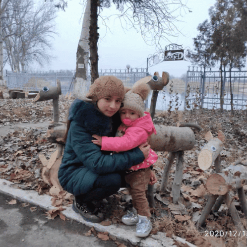 a child and adult sit on the ground with burned fire hydrant