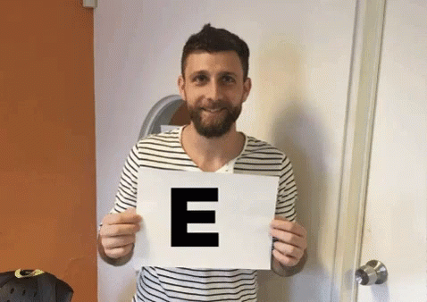 a man is holding up a paper that reads e