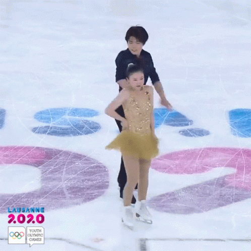 two figure skating on a ice rink with the olympic logo
