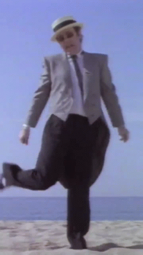 a man in a suit is running through the sand