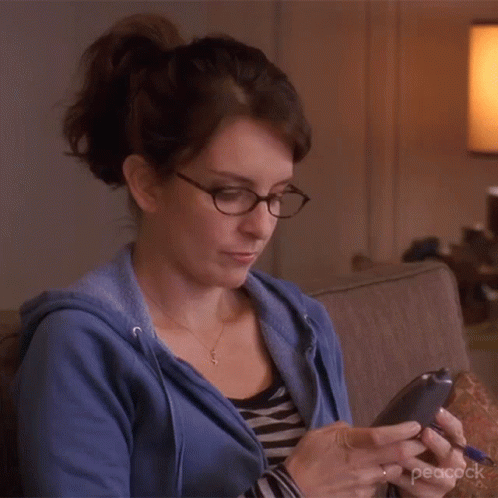 a woman looking at her phone while sitting on a couch