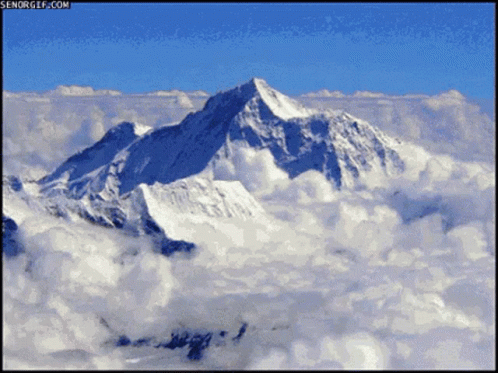 a snow covered mountain in the middle of clouds