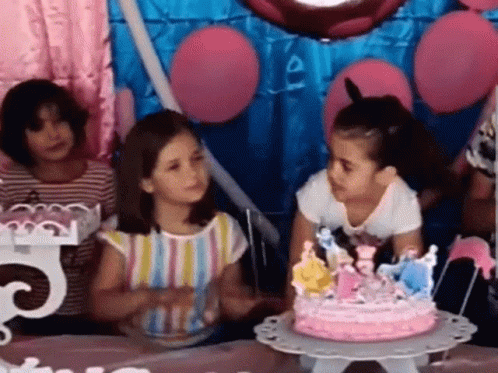 three children sit around a cake with candles