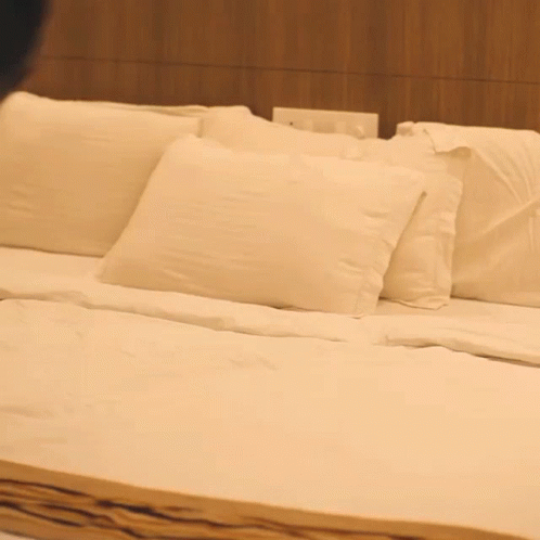 a bed with four pillows and blue sheets