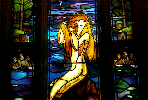 a beautiful woman standing behind a stained glass window