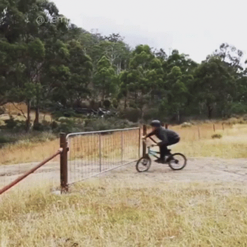 a man is riding a bike over a fence