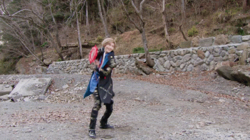 a person with a bunch of stuff walking on some gravel