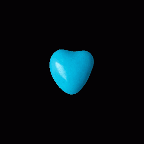 a yellow heart shaped object floating on black surface