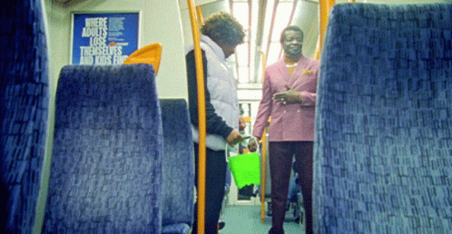 a pair of women stand inside a bus with an empty green bucket