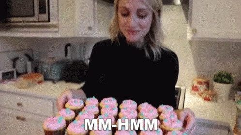 a woman looking through a box of cupcakes