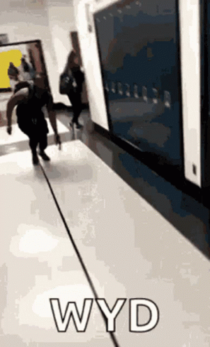 three people are walking down a hallway with large screens