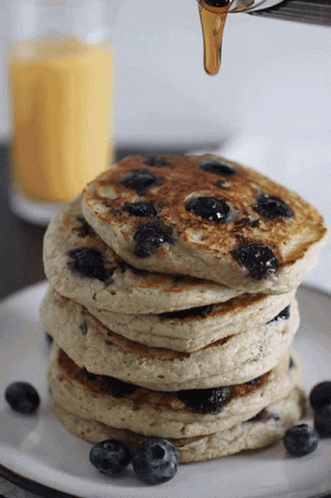 a white plate holding a stack of blueberry pancakes
