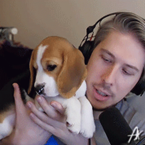 the young man is wearing headphones while holding his puppy