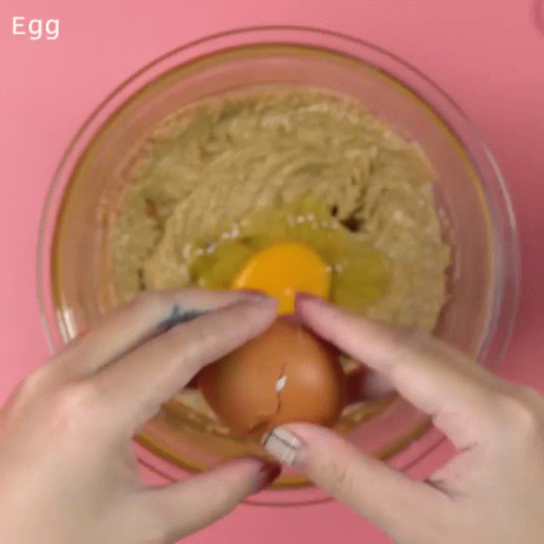 hands holding an egg up in a bowl