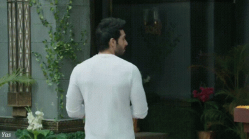 a man in a white suit walking into the front door of a building